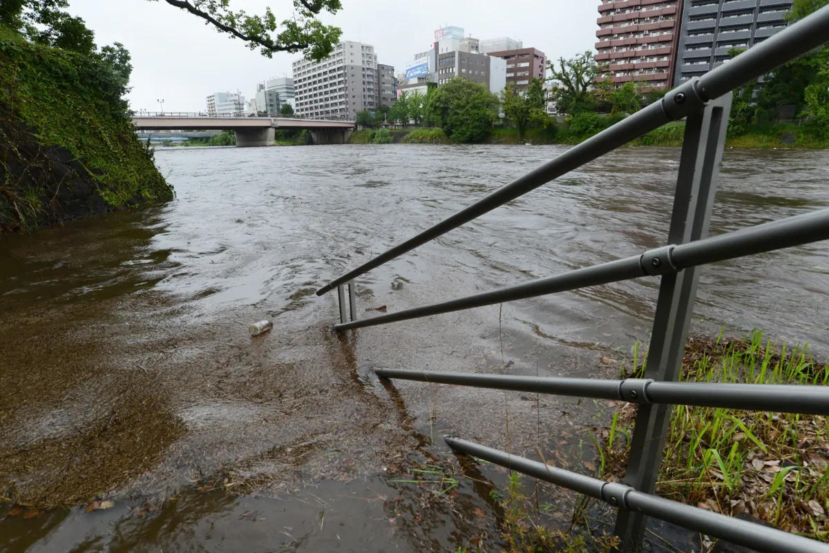 Part of a handrail sits submerged after the Shirakawa River in the city of Kumamoto, Kumamoto Prefecture, rose following heavy rains across the Japanese island of Kyushu on June 30, 2023. (STR/JIJI Press/AFP via Getty Images)