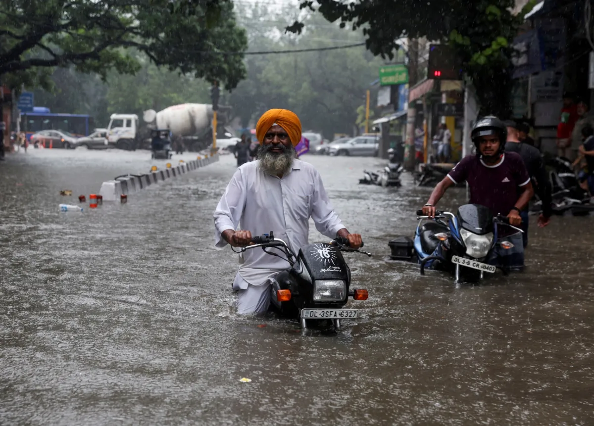 A man on his motorbike wades through a flooded street after heavy rains in New Delhi on July 8, 2023. (Anushree Fadnavis/Reuters)