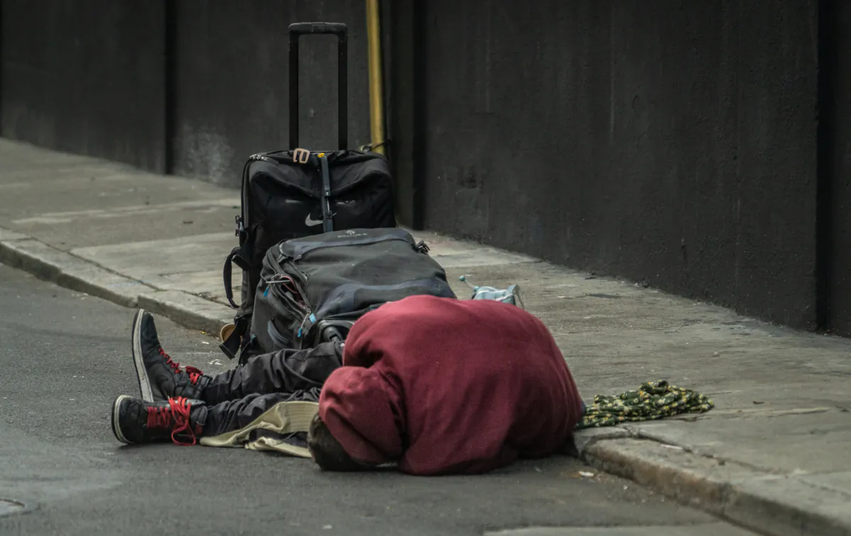 A homeless man lies on the street in the Tenderloin District of San Francisco on Feb. 23, 2023. (John Fredricks/The Epoch Times)