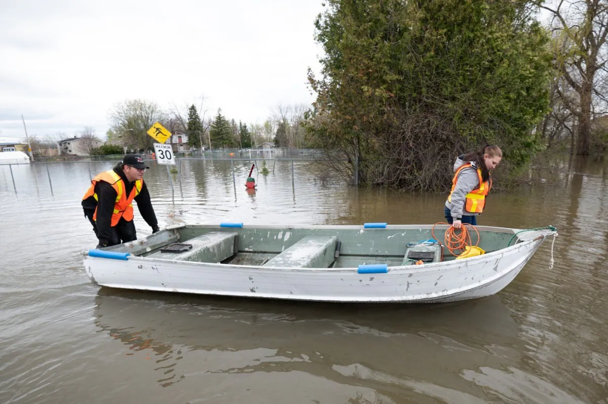 Kévin Masson, left, and Mélody Bastien, local residents of Cantley, Que., make their way to dry land after searching and assisting in the evacuation of local residents, on May 4, 2023. (The Canadian Press/Spencer Colby)

