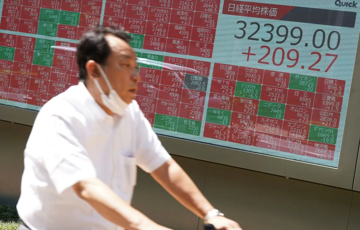 A person rides a bicycle in front of an electronic stock board showing Japan's Nikkei 225 index at a securities firm in Tokyo on July 11, 2023. (Eugene Hoshiko/AP Photo)