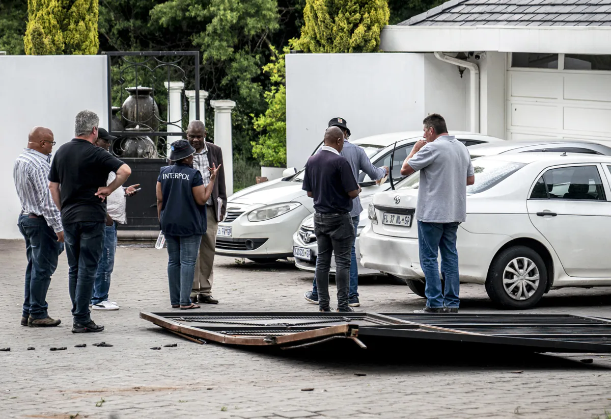 Following the arrest of an Israeli fugitive various South African Police Service (SAPS) units—including Interpol officers—stand next to a gate lying on the ground at a house in Bryanston, Johannesburg, on Nov. 17, 2022. (AFP via Getty Images)