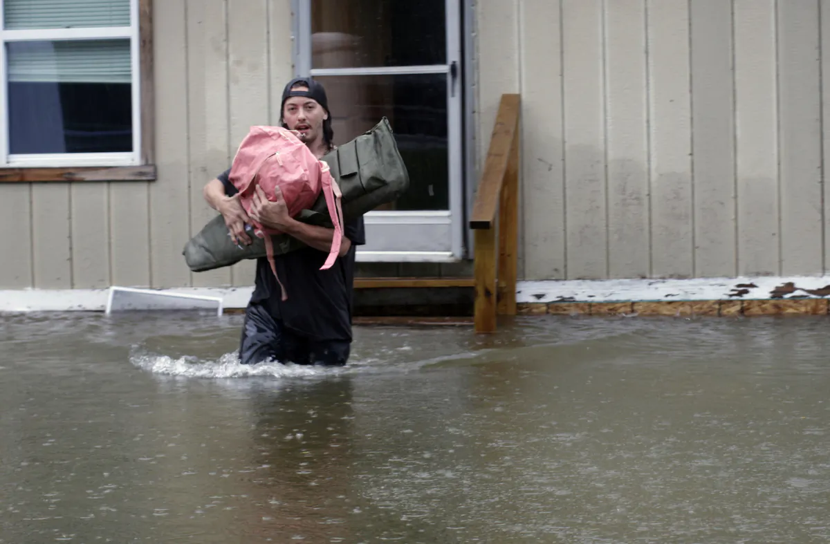 A man carries belongings through floodwaters from a home in Bridgewater, Vt., on July 10, 2023. (Hasan Jamali/AP Photo)