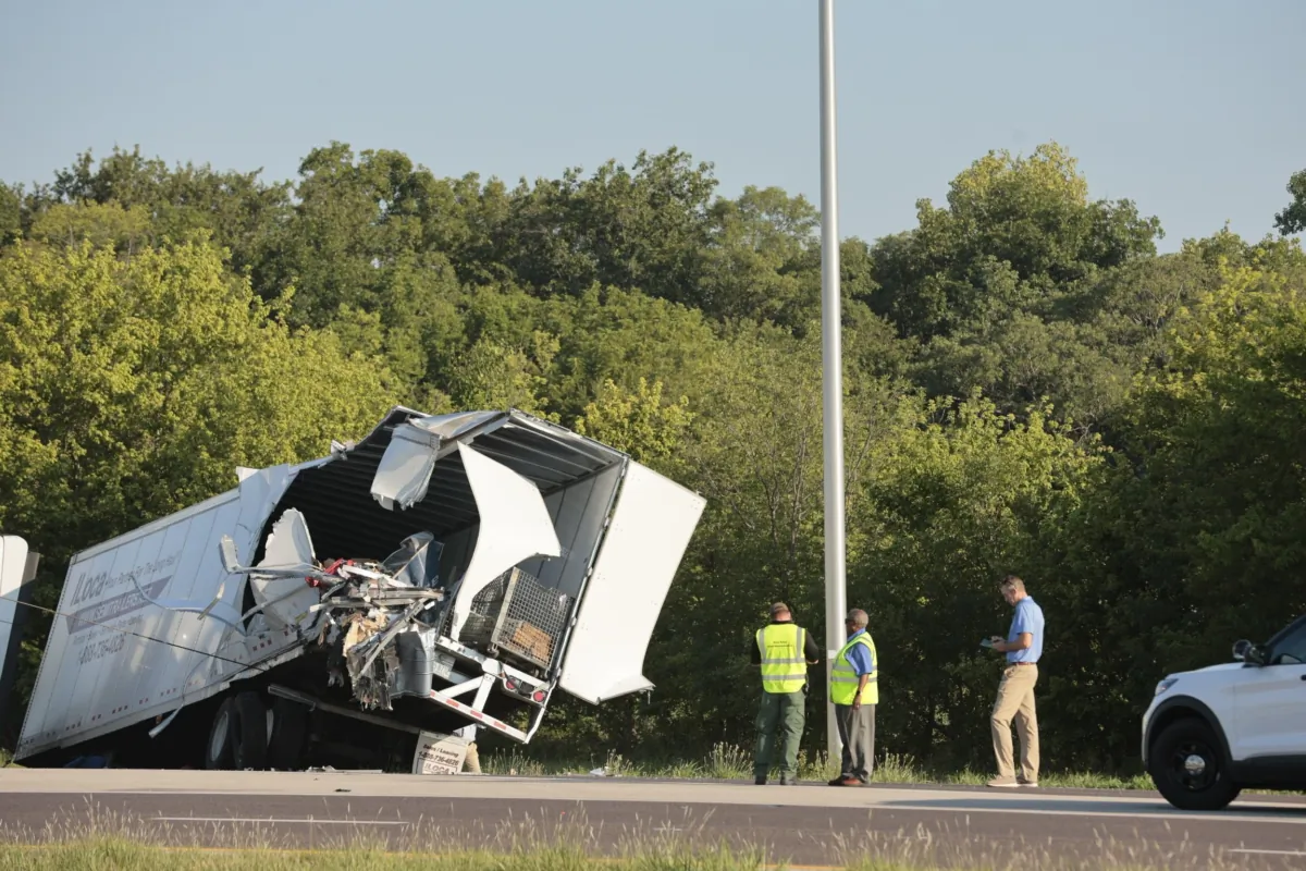 Officials examine a wrecked tractor-trailer that a Greyhound bus collided with on the exit ramp to a rest area on westbound Interstate 70 in Highland, Ill., on July 12, 2023. (Christian Gooden/St. Louis Post-Dispatch via AP)