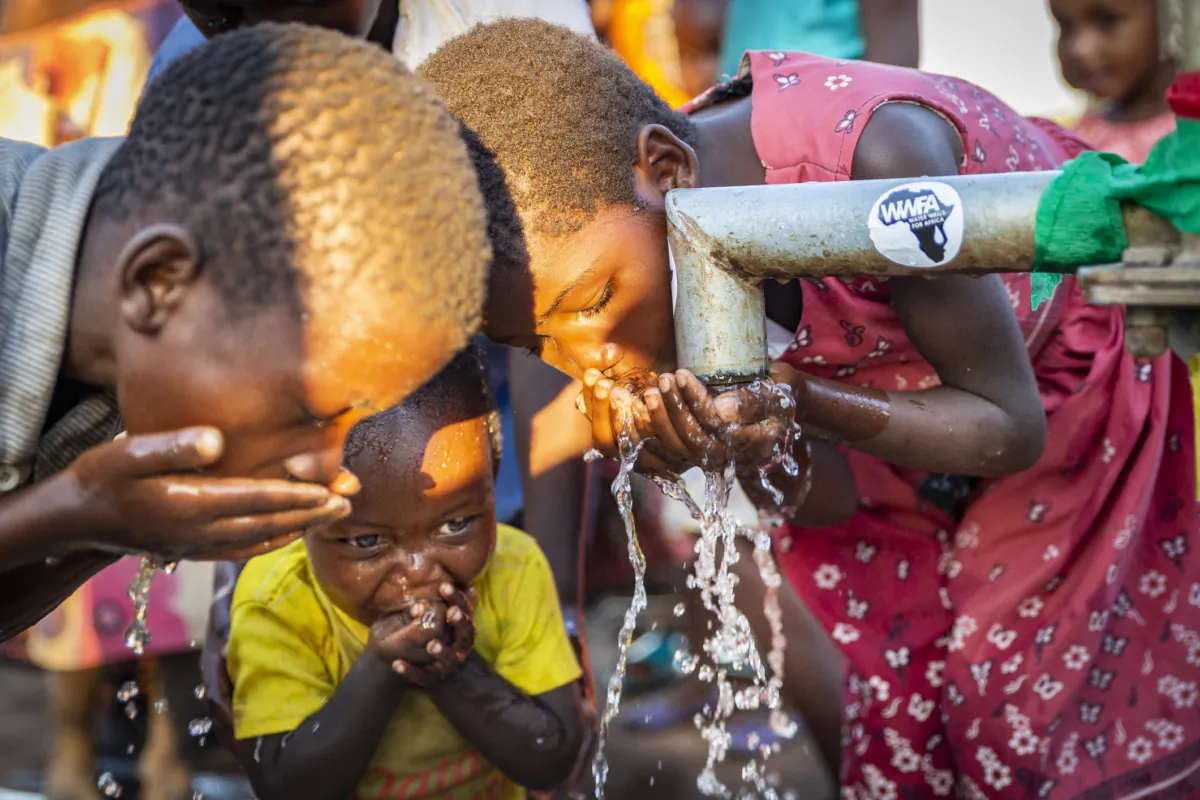 Children enjoy clean water from a well built by Water Wells for Africa in Maggie B Village, Malawi, on June 30, 2021.(John Fredricks/The Epoch Times)