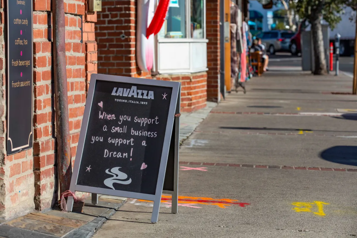 A sign in favor of small business sits on the sidewalk in front of The Rocky Mountain Chocolate Factory in Laguna Beach, Calif., on Nov. 18, 2020. (John Fredricks/The Epoch Times)