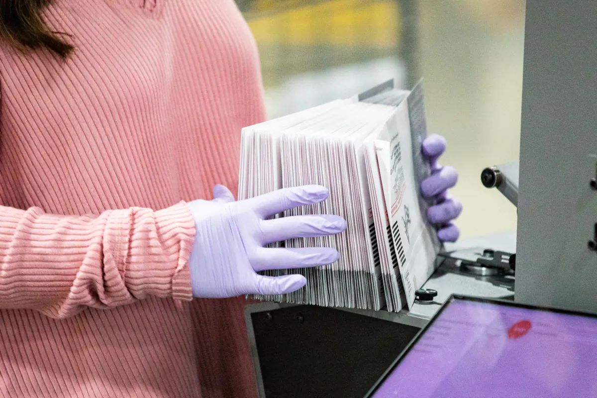 An election worker  holds ballots at a voting location. (John Fredricks/The Epoch Times)