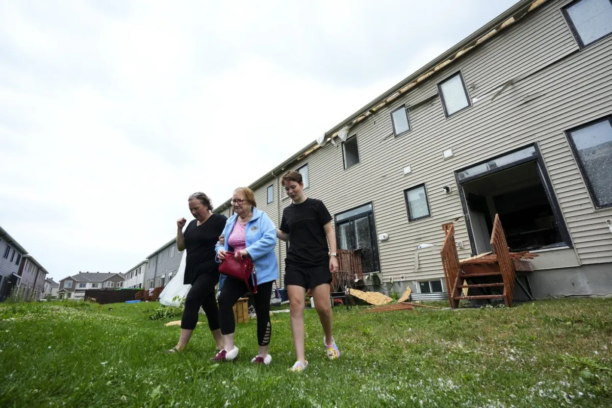 Helen Feltham, 82, is helped from her home by her daughter and granddaughter after it was damaged by a tornado in the Ottawa suburb of Barrhaven on July 13, 2023. (The Canadian Press/Sean Kilpatrick)
