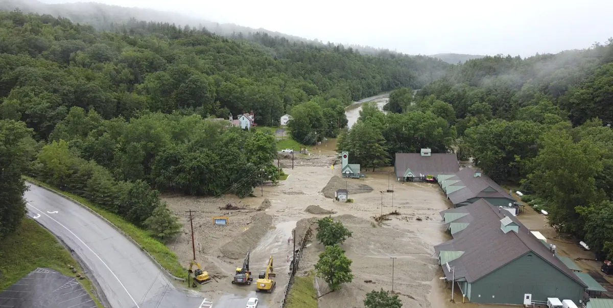 Construction vehicles stand by as muck, mud and floodwater block a section of Route 203 in Ludlow, Vt., on July 11, 2023. (Pat Moore via AP)