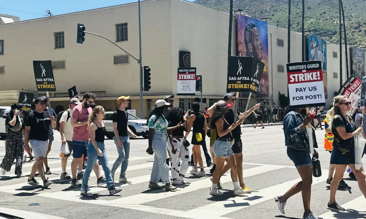 Members of the Screen Actors Guild-American Federation of Television and Radio Artists (SAG-AFTRA) on strike march with signs in front of Warner Bros. Studios in Burbank, Calif., on July 14, 2023. (Jill McLaughlin/The Epoch Times)