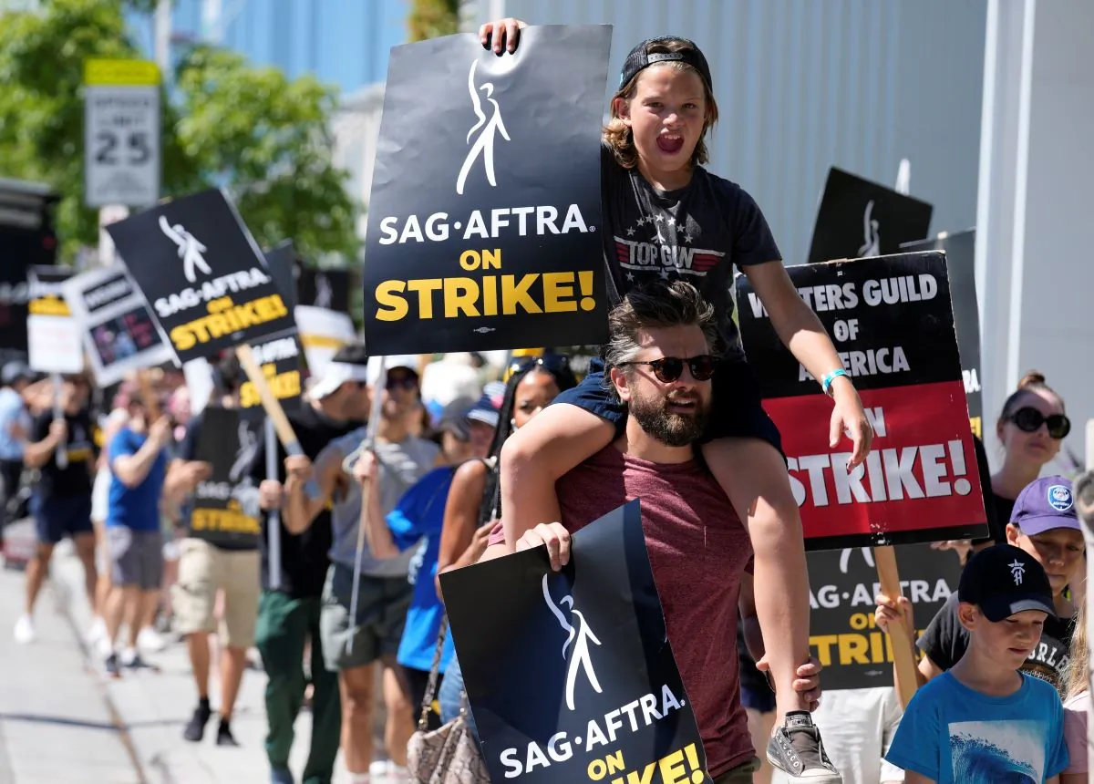 Actor Jac Cheairs and his son Wyatt, 11, take part in a rally by striking writers and actors outside Netflix studio in Los Angeles on Friday, July 14, 2023. (AP Photo/Chris Pizzello)