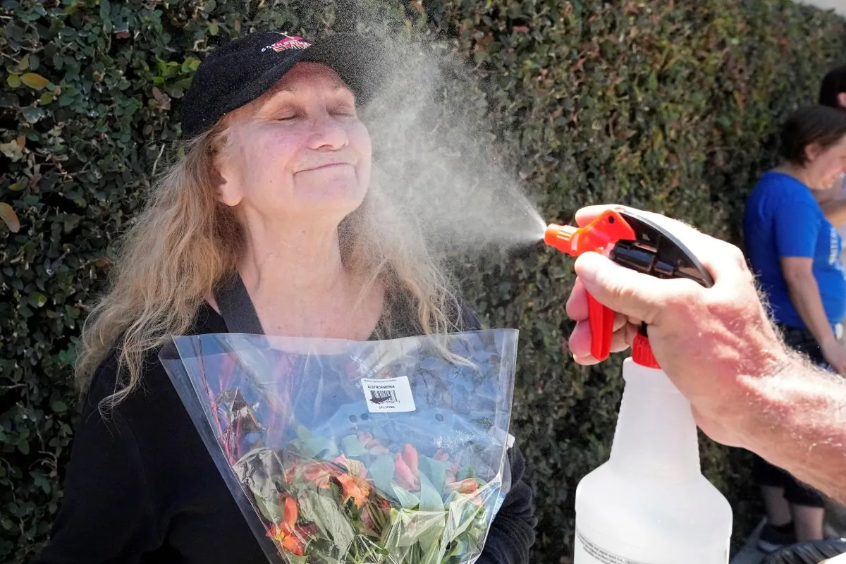 Marbry Steward (L) gets a cooling spritz of water from Michael Abel during a rally by striking writers and actors outside Warner Bros. studios, in Burbank, Calif., on July 14, 2023. (Mark J. Terrill/AP Photo)