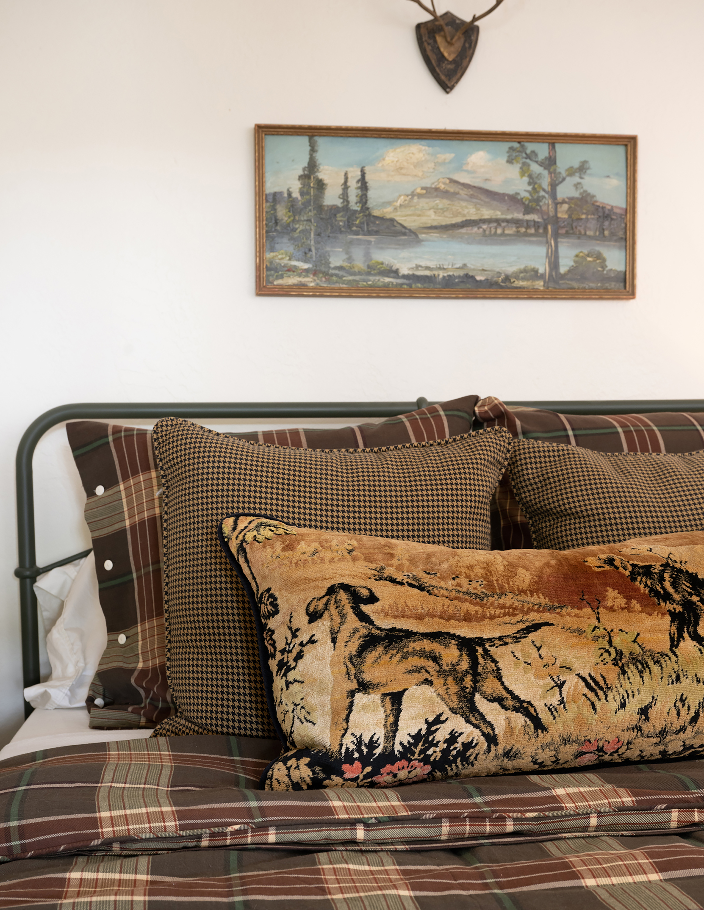 A one-of-a-kind pillow on the bed catches the eye, crafted from an antique tapestry discovered during an antiquing adventure.
