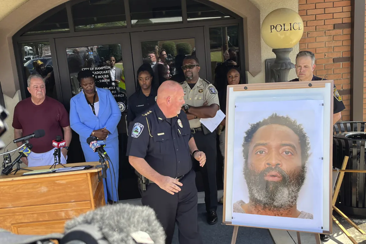 Hampton Police Chief James Turner (C) stands next to a mounted picture of suspect Andre Longmore during a news conference in Hampton, Ga., on July 15, 2023. (Steve Gehlbach/WSB-TV via AP)