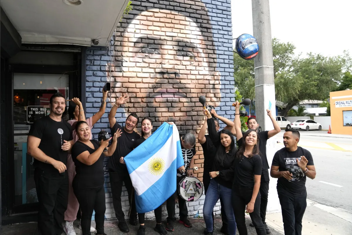 Staff at the Fiorito restaurant pose in front of a mural of Lionel Messi to celebrate after the Argentine soccer star announced he is joining the Major League Soccer team Inter Miami in Miami on June 7, 2023. (Lynne Sladky/AP Photo)