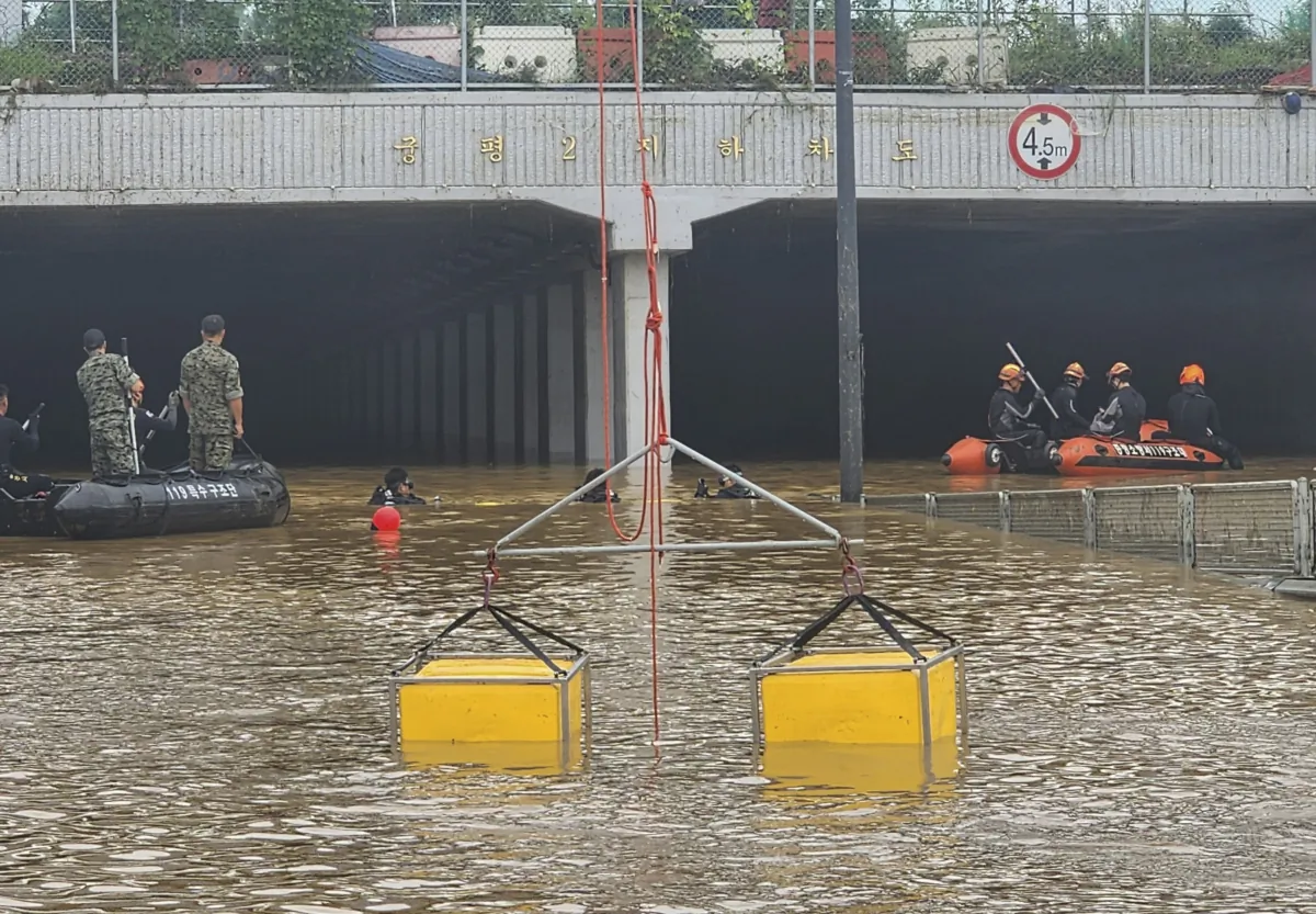 Rescuers search for survivors along a road submerged by floodwaters leading to an underground tunnel in Cheongju, South Korea, on July 16, 2023. (South Korea National Fire Agency via AP)