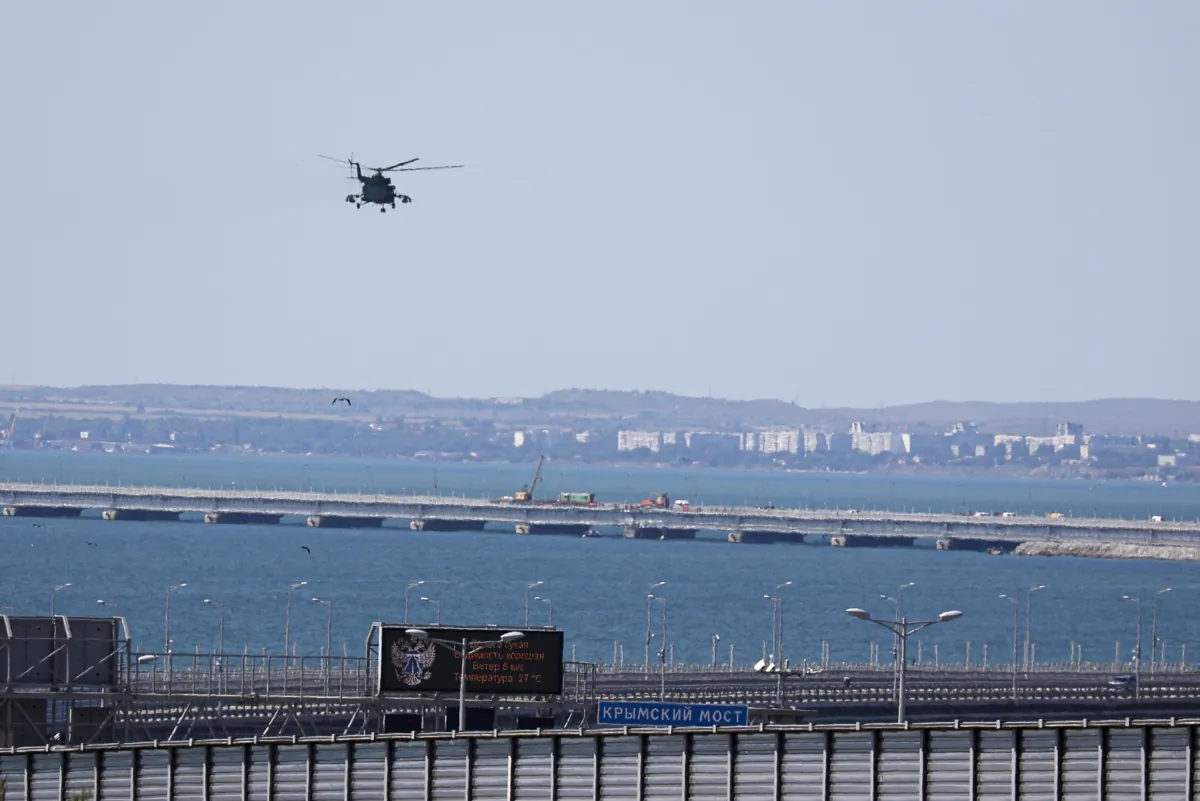A Russian military helicopter flies over damaged parts of an automobile link of the Crimean Bridge connecting Russian mainland and Crimean peninsula over the Kerch Strait not far from Kerch, Crimea, on July 17, 2023. (AP Photo)