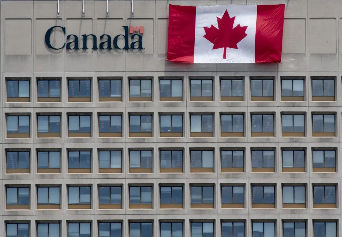 A giant Canadian flag hangs on the side of a government office building in downtown Ottawa, on June 30, 2020. (Adrian Wyld/The Canadian Press)