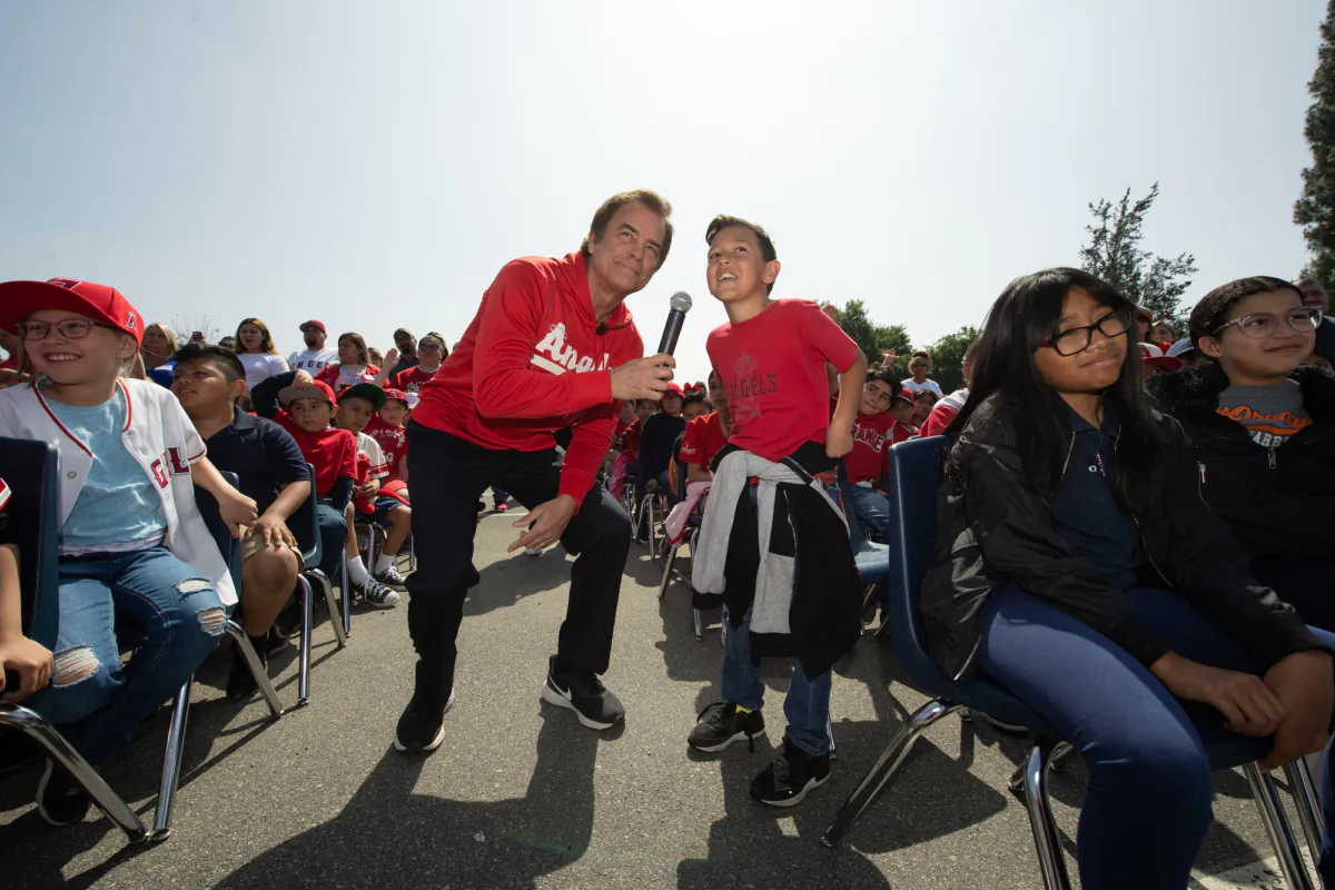 Sports talk show host Roger Lodge interacts with a student at an Angels Adopt-A-School event at West Orange Elementary School in Orange, Calif., on April 26, 2023. (Courtesy of Angels Radio AM 830)