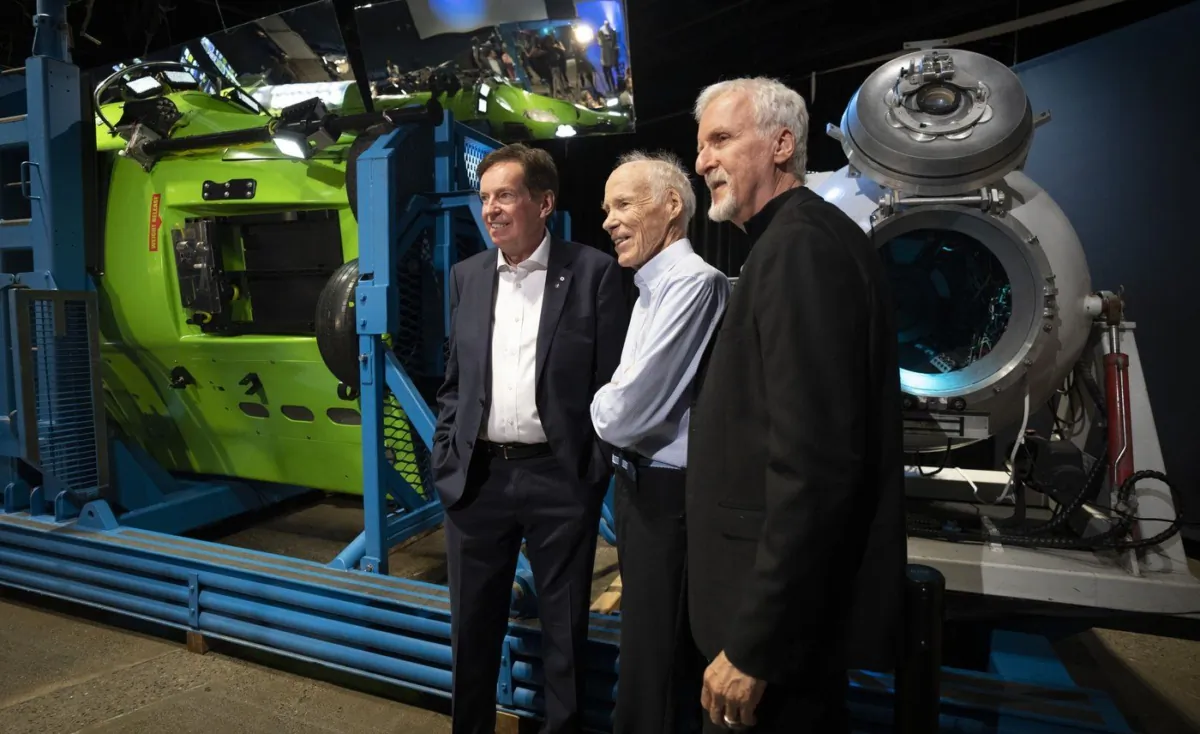 Canadian Geographic President and CEO John Geiger (L), scientific adviser Joe MacInnis and explorer and filmmaker James Cameron pose for a photo in front of the Deepsea Challenger and a capsule on display at the Royal Canadian Geographic Society, July 18, 2023 in Ottawa. (The Canadian Press/Adrian Wyld)
