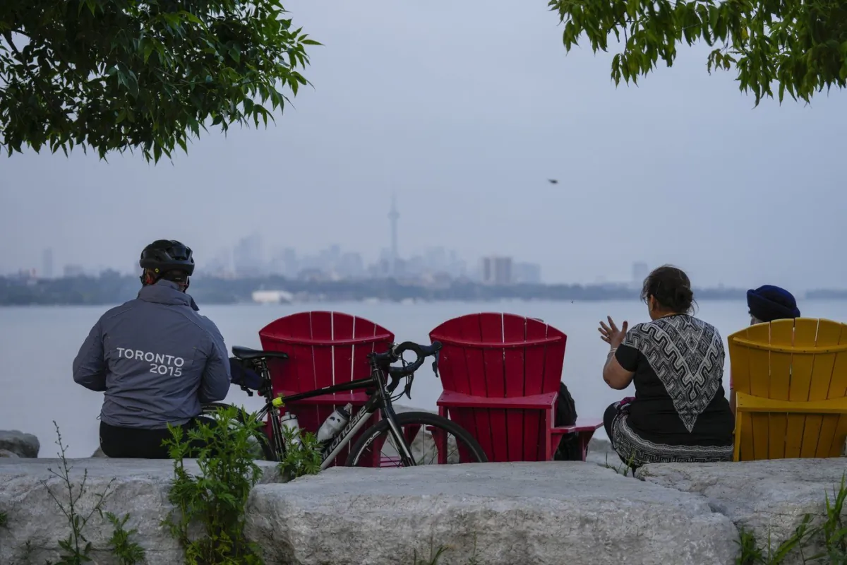 People sit along the waterfront at Humber Bay Park in Toronto on Wednesday, June 28, 2023. (The Canadian Press/Andrew Lahodynskyj)