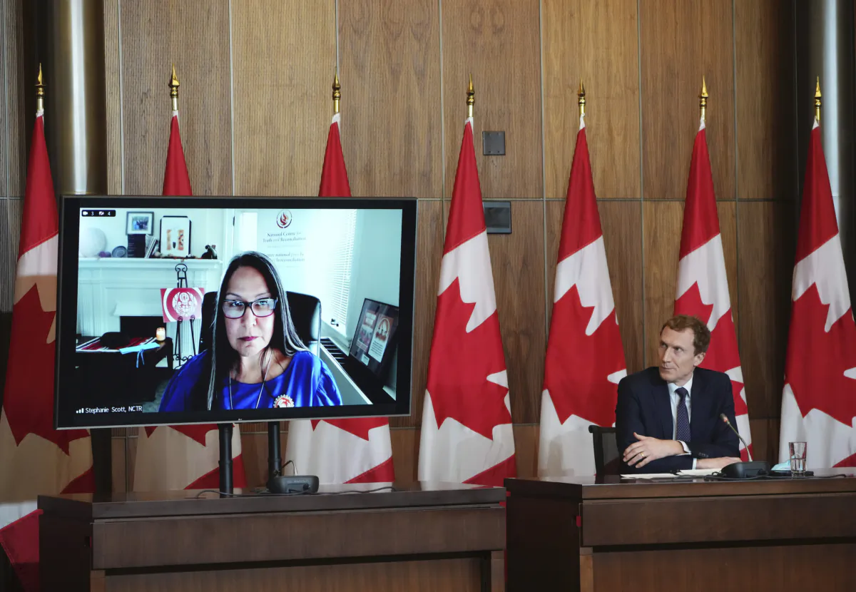 Minister of Crown-Indigenous Relations Marc Miller and Executive Director of the National Centre for Truth and Reconciliation Stephanie Scott (virtually on monitor) listen to a question from media during a press conference in Ottawa on Jan. 20, 2022. (THE CANADIAN PRESS/Sean Kilpatrick)