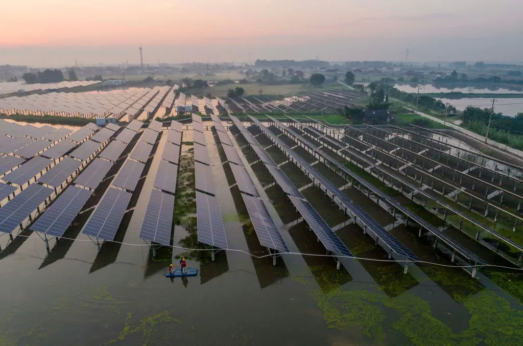 Workers inspect solar panels in the early morning at the fishing-solar complementary photovoltaic power generation base in Taizhou, in China's eastern Jiangsu province on July 12, 2023. (Stringer/AFP via Getty Images)