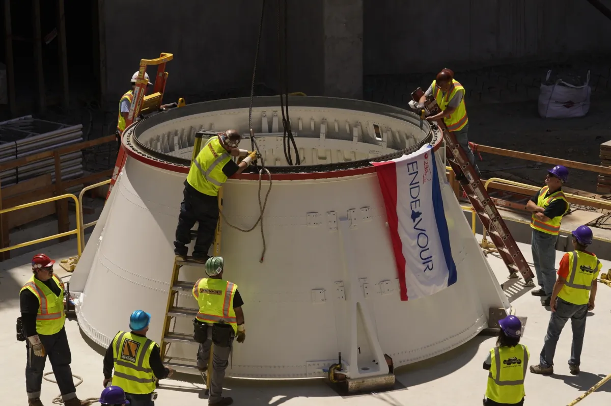 Technicians remove lifting lugs after placing the Space Shuttle Endeavour's Solid Rocket Aft Skirts on top of a seismic isolator pad in the Shuttle Gallery of at the Samuel Oschin Air and Space Center in Los Angeles on July 20, 2023. (Damian Dovarganes/AP Photo)