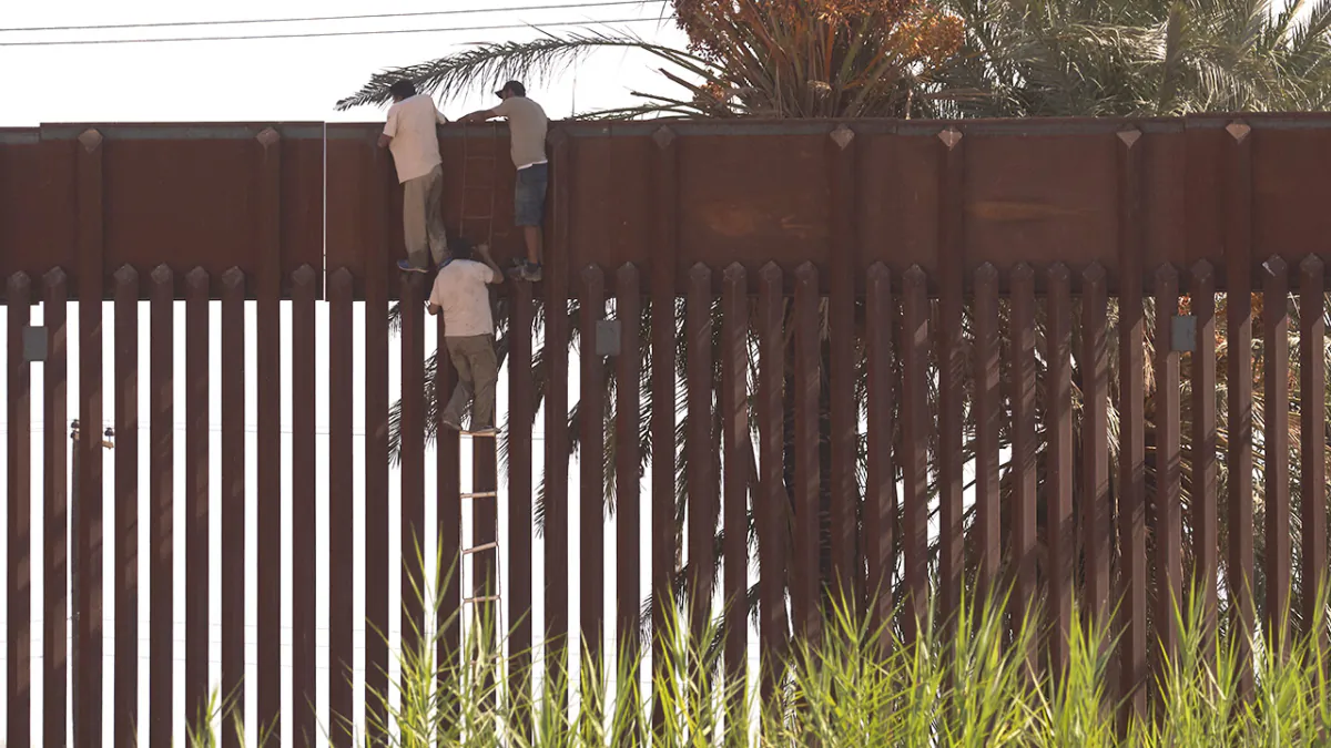 Migrants use a rope ladder to illegally climb over the U.S. border wall separating the United States from Mexico in El Centro, Calif. on Oct. 6, 2022. (Allison Dinner/AFP via Getty Images)