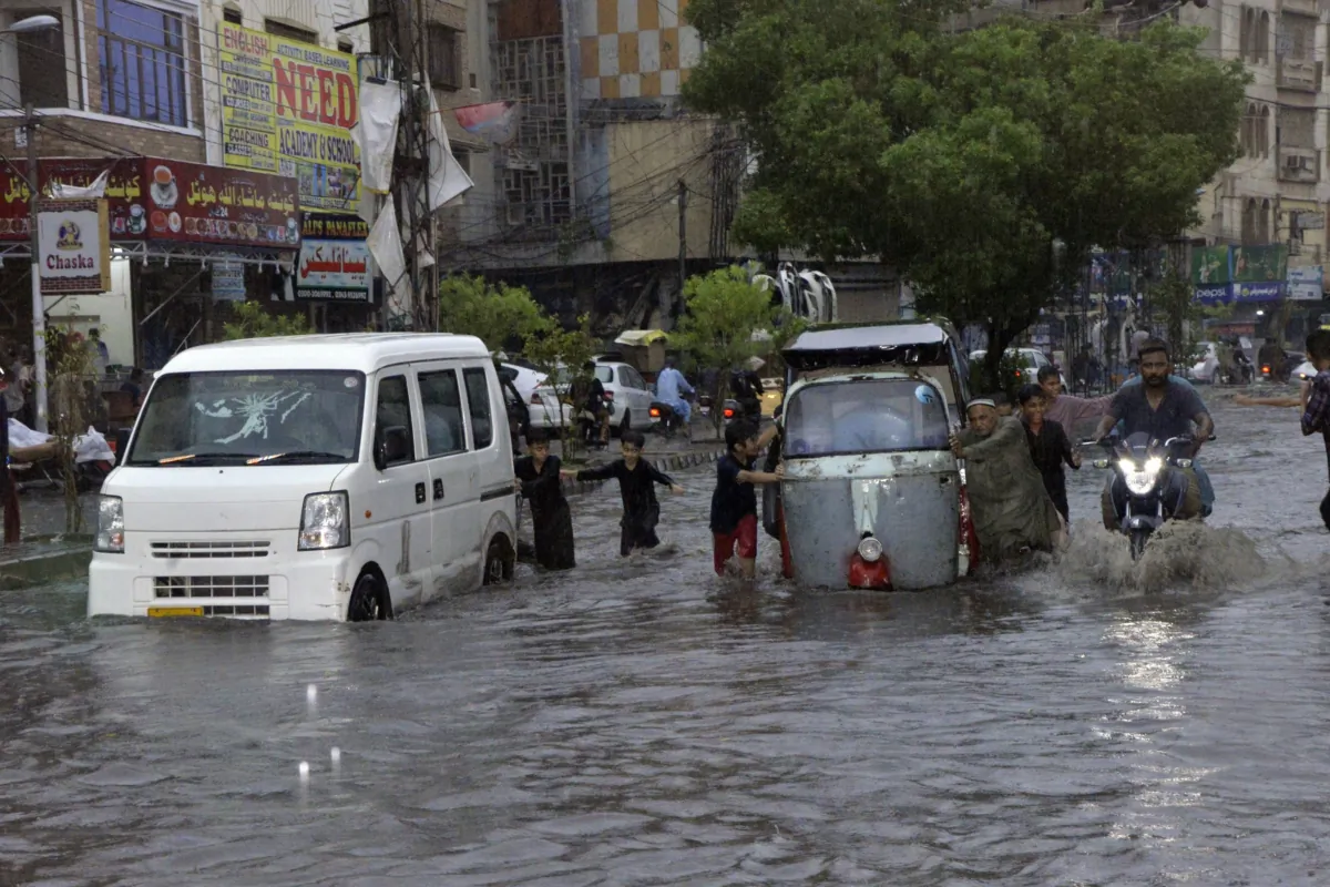 Motorcyclists and cars drive through a flooded road caused by heavy monsoon rainfall in Karachi, Pakistan, on July 23, 2023. (Fareed Khan/AP Photo)
