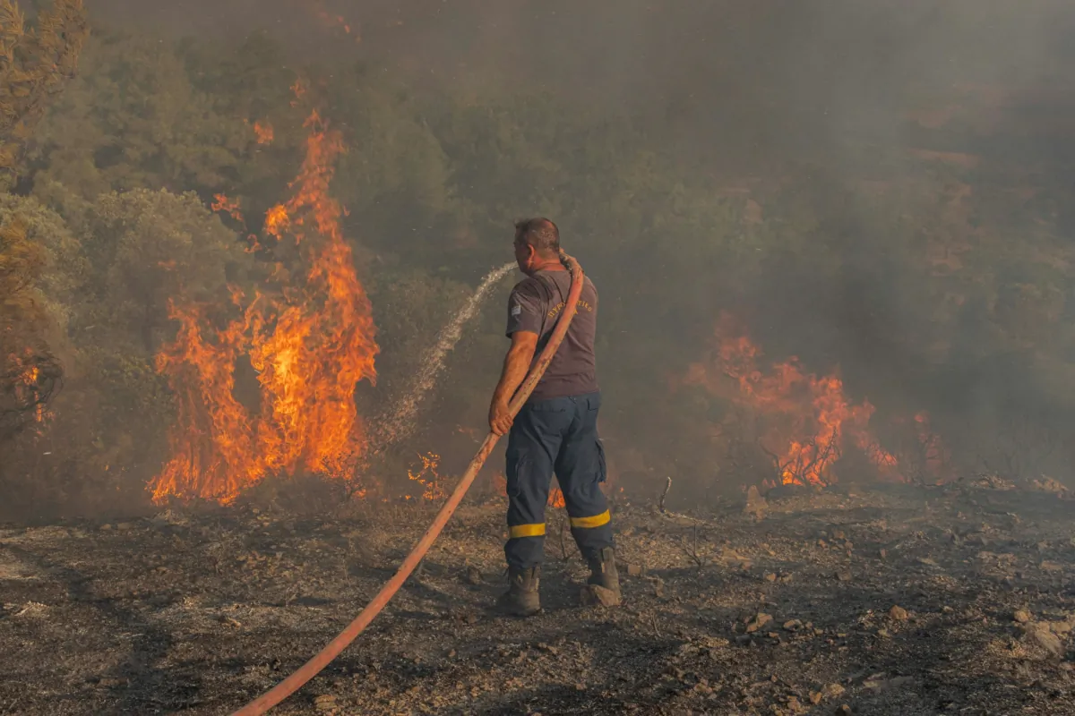 Firefighter Nektarios Kefalas tries to extinguish a wildfire burning near the village of Asklipieio, on the island of Rhodes, Greece, on July 24, 2023. (Nicolas Economou/Reuters)