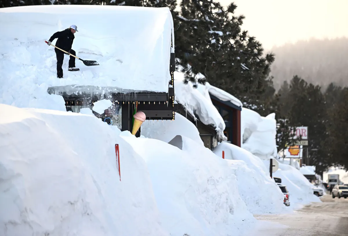 Owner Brang Miller shovels snow off the roof of Mammoth Fun Shop and locals try to dig out in between storms in Mammoth Mountain, California, March 7, 2023. (Wally Skalij/Los Angeles Times/TNS)