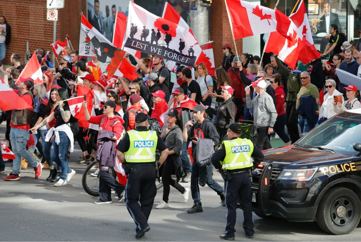 People march past police at a demonstration, part of a convoy-style protest, in Ottawa on April 30, 2022. (The Canadian Press/Patrick Doyle)