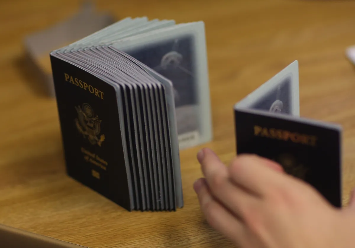 A passport-processing employee uses a stack of blank passports to print a new one at the Miami Passport Agency in Miami on June 22, 2007. (Joe Raedle/Getty Images)