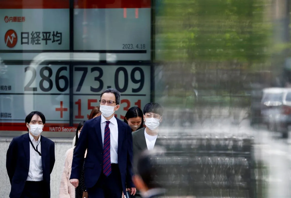 Passersby walk past an electric board displaying Japan's Nikkei share average outside a brokerage in Tokyo, Japan, on April 18, 2023. (Issei Kato/Reuters)