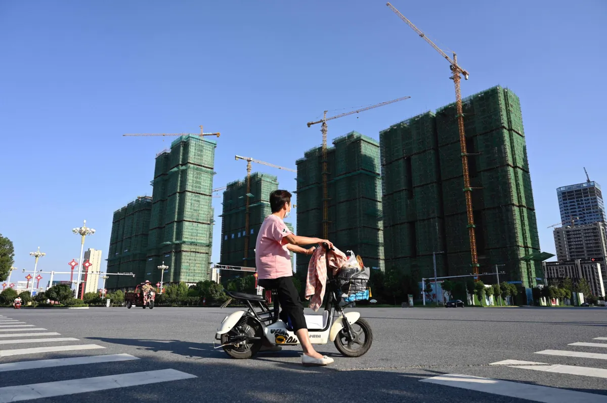 A woman rides a scooter past the construction site of an Evergrande housing complex in Zhumadian, central China's Henan Province, on Sept. 14, 2021. (Jade Gao/AFP via Getty Images)