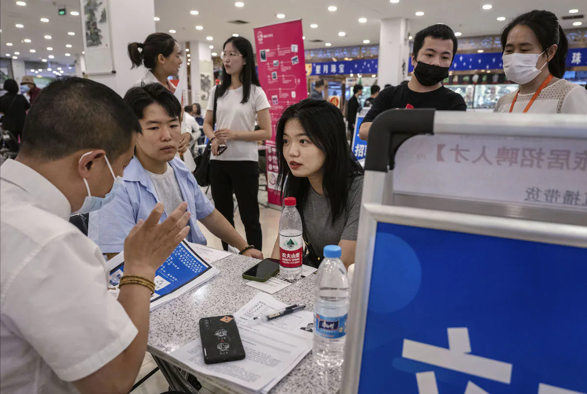 A young man and woman talk to a recruiter as they seek employment at a job fair on June 9, 2023 in Beijing, China. (Kevin Frayer/Getty Images)