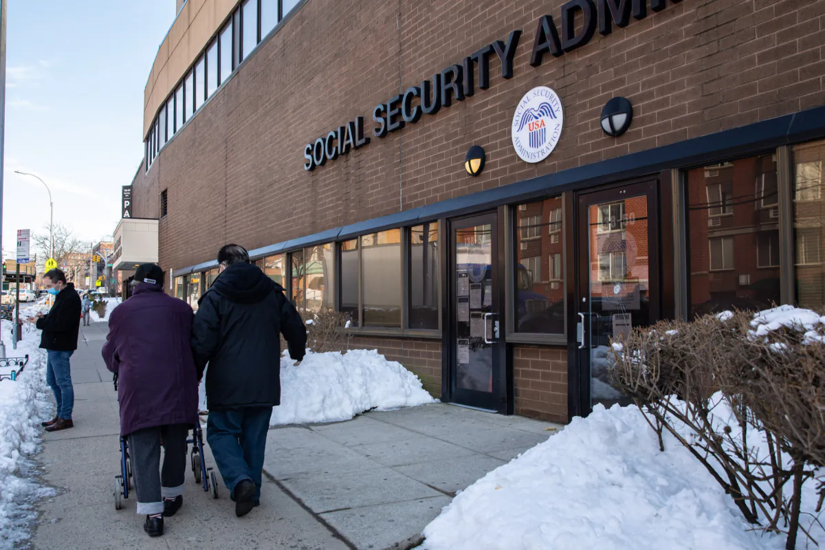 An elderly couple walk past a Social Security Administration in Flushing, New York, during the COVID-19 pandemic on Feb. 10, 2021. (Chung I Ho/The Epoch Times)