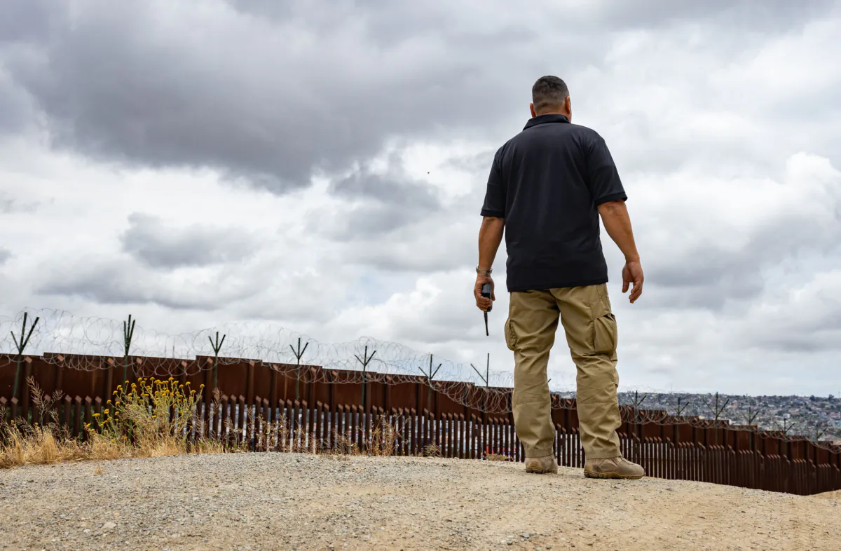 A border patrol agent listens to radio chatter at the border wall near San Diego, Calif., on May 31, 2023. (John Fredricks/The Epoch Times)