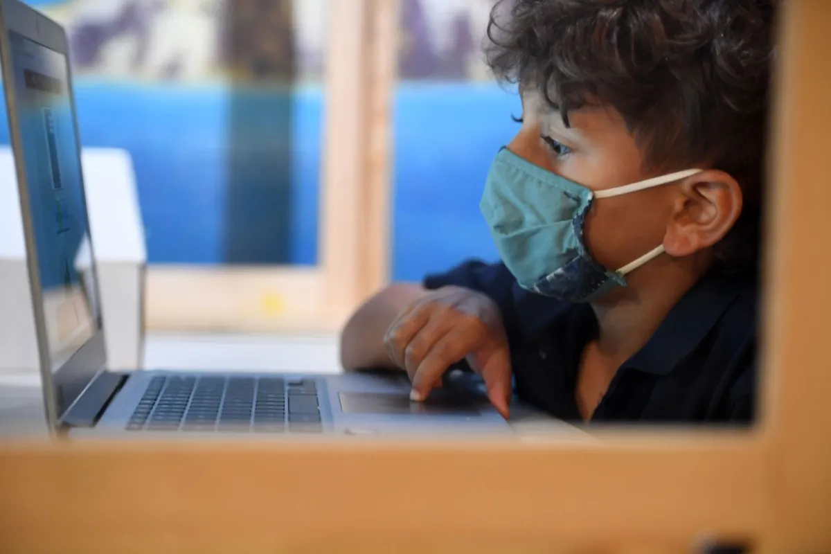 A student follows along remotely with their regular school teacher's online live lesson from a desk separated from others by plastic barriers at STAR Eco Station Tutoring & Enrichment Center in Culver City, Calif., on Sept. 10, 2020. (Robyn Beck/AFP via Getty Images)