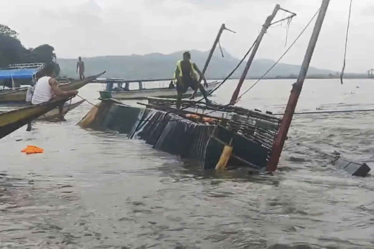 A man stands on a capsized passenger boat as they undergo rescue operations at Binangonan, Rizal province, east of Manila, Philippines, on July 27, 2023. (Philippine Coast Guard via AP)