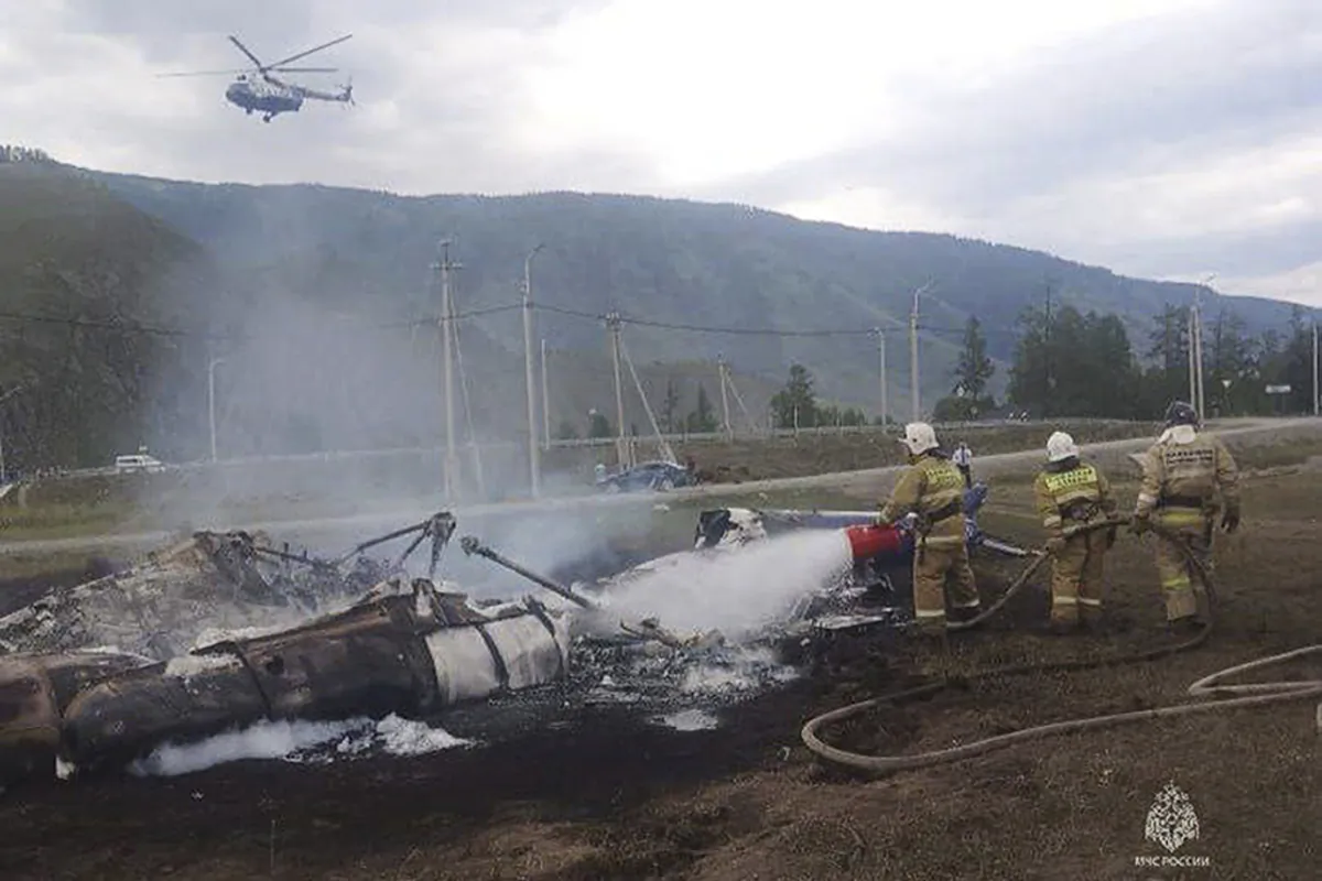 Firefighters extinguish a Mi-8 helicopter after the crash near Tyungur village, Altai Republic, in southern Siberia, Russia, on July 27, 2023. (Ministry of Emergency Situations press service via AP)