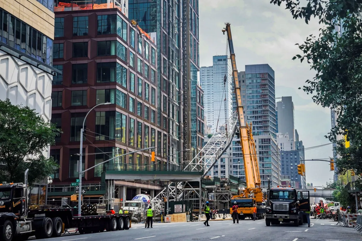 A ground crane lifts the extension arm from a hi-rise construction crane, which broke away on Wednesday and plummeted to the street after the crane caught fire in New York on July 27, 2023. (Bebeto Matthews/AP Photo)