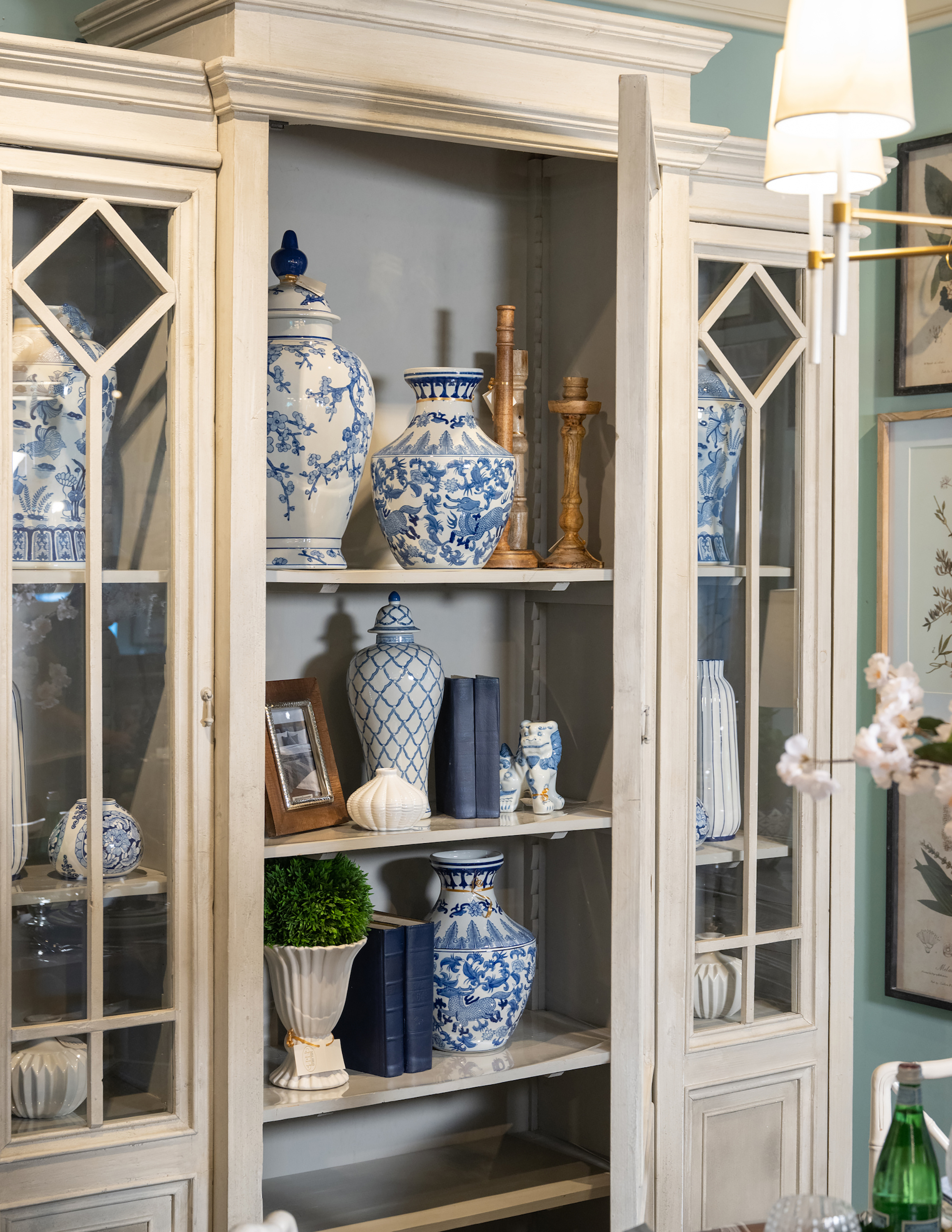 An etagere designed to exude a formal aesthetic, boasting glass shelves and brass finishings, complemented by an acrylic bar handle.