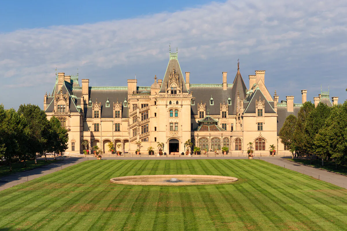 The French Renaissance chateau style design, with Gothic elements, invoked both grandeur and symmetry. The three-story mansion’s façade conveys an open top deck, wide arched doorway, decorative spires, cornices featuring carved gargoyles, and a windowed spiral staircase.  (ZakZeinert/Shutterstock)