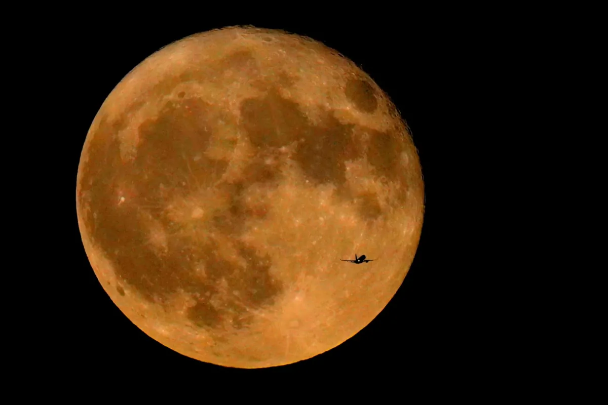 A commercial airliner flies Northwest across Lake Michigan in front of the "Full Buck" supermoon, the first of four supermoons in 2023, in Chicago on July 3, 2023. (Charles Rex Arbogast/AP Photo)