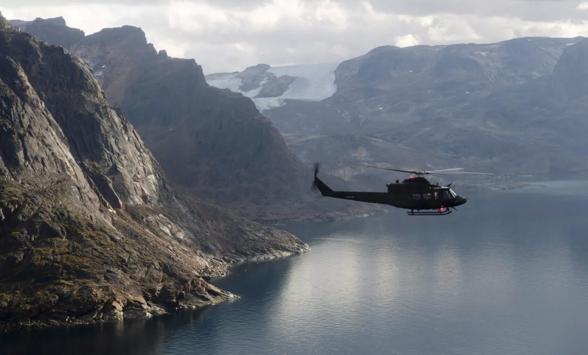 A Canadian military Griffon helicopter flies along the shoreline of Baffin Island as it moves personnel between Operation Nanook and Iqaluit, on Aug. 26, 2014. (The Canadian Press/Adrian Wyld)