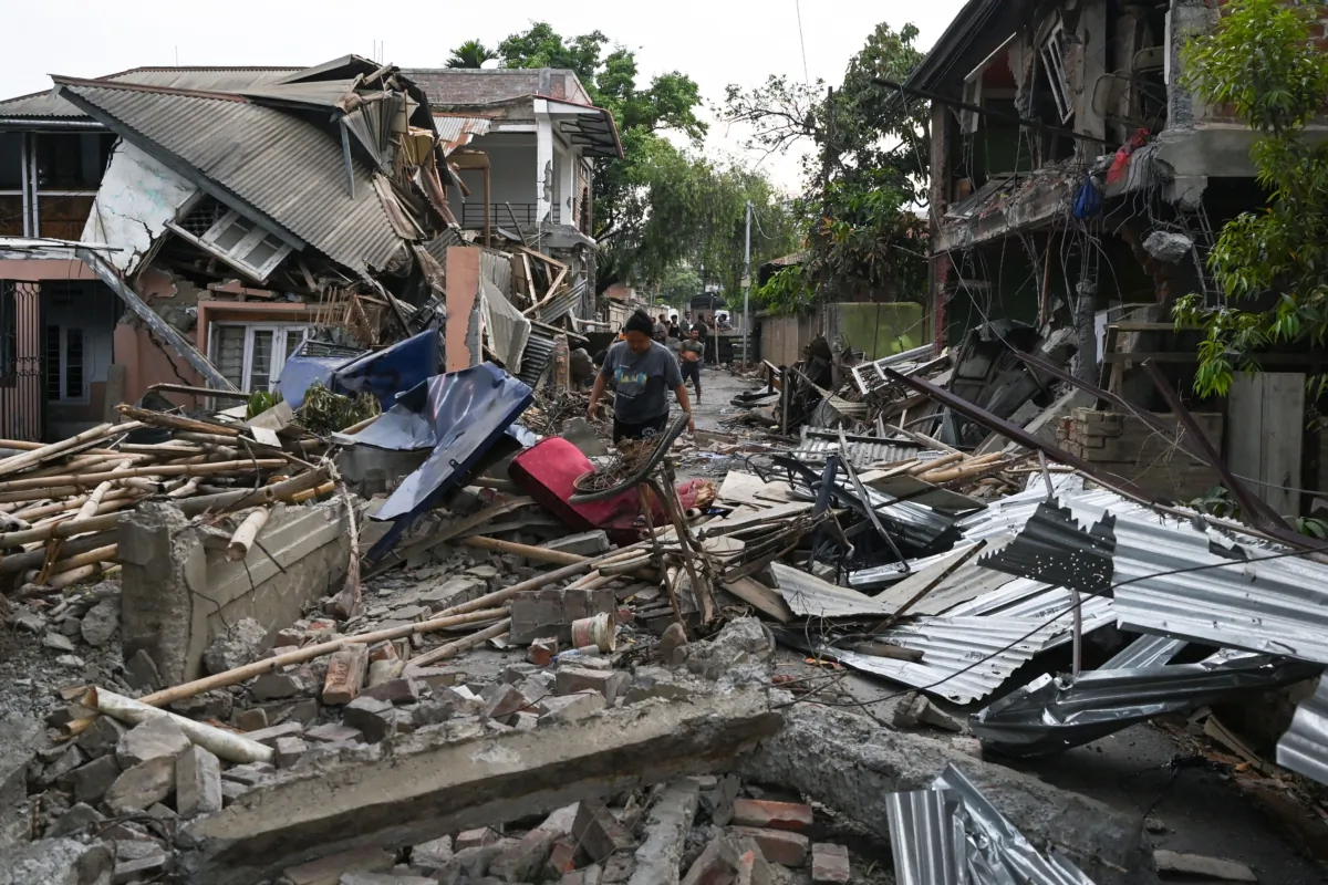 A woman walks through the wreckage of a building that was set on fire and vandalized by mobs in Khumujamba village on the outskirts of Churachandpur on May 9, 2023, in an area hit by violence in the northeastern Indian state of Manipur. (Arun Sankar/AFP via Getty Images)