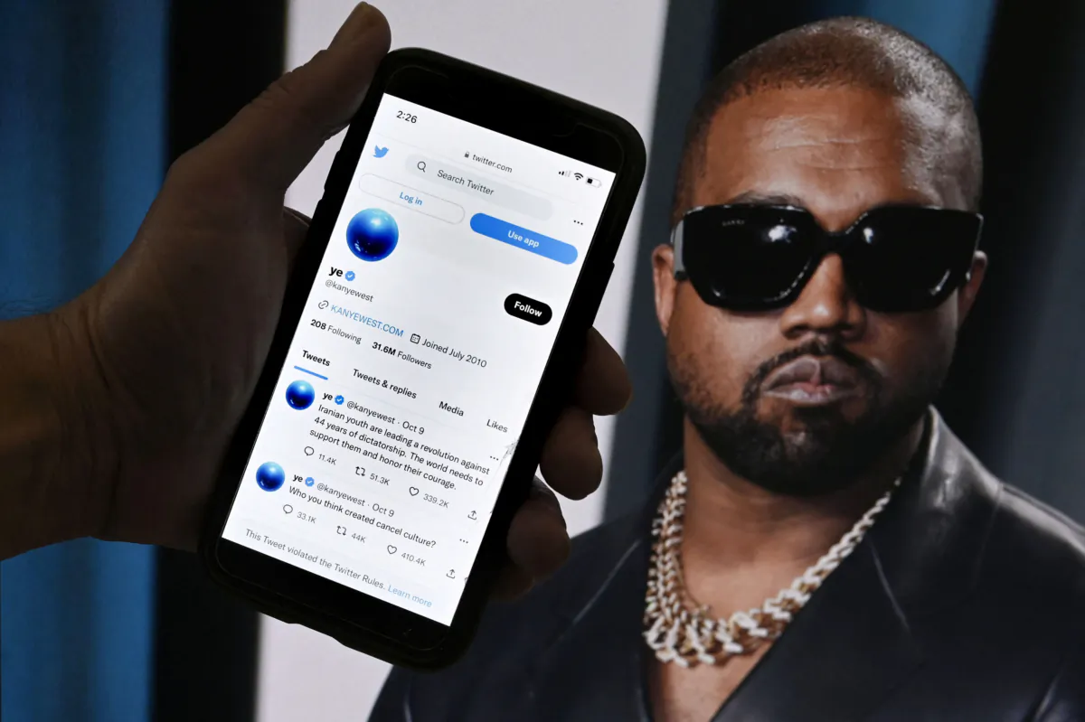 The Twitter account of Kanye West is displayed on a mobile phone with a photo of him shown in the background in Washington on Oct. 28, 2022. (Olivier Douliery/AFP via Getty Images)