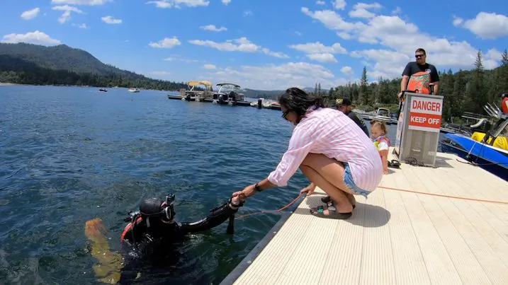 Mike Pelley, also known as ‘Merman Mike’, hands Jennie Boles her lost wedding ring that he found in Bass Lake in Northern California on June 25, 2023.(Courtesy of Merman Mike)